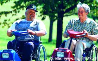In der Abbildung sind zwei Rollstuhlfahrer bei einem Ausflug zu sehen.